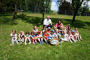 Bürgermeister Thomas Steiner mit vielen Kindern und Blumensamen auf einer Wiese im Kindergarten